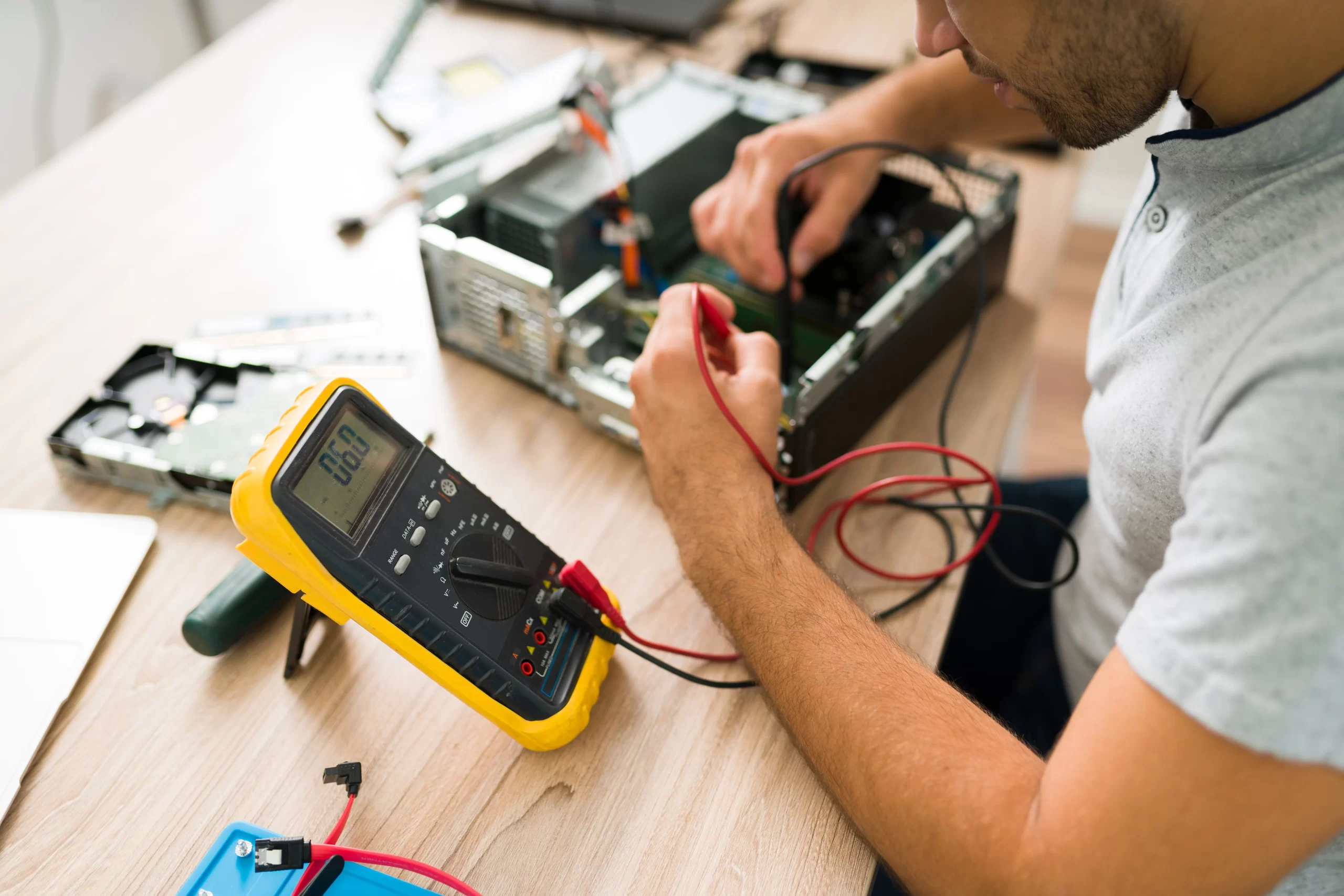 technician using multimeter measure voltage broken computer young man checking computer connections repair shop scaled